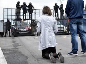 A demonstrator kneels in front of law enforcement officers blocking an area in front of the Independence Palace during a rally of opposition supporters to protest against disputed presidential election results in Minsk on August 23, 2020. Tens of thousands of demonstrators massed in central Minsk on August 23 to demand the resignation of Belarusian President Alexander Lukashenko, the latest in a wave of protests against his disputed re-election. Sergei GAPON / AFP