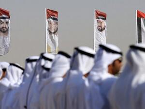 Emirati men perform a traditional dance in front of flags bearing portraits of Abu Dhabi's Crown Prince Sheikh Mohammed bin Zayed al-Nahyan, February 9, 2016. (AFP/Karim Sahib/ File)