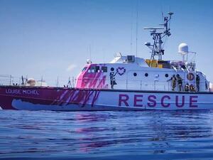 Painted in bright pink and featuring Banksy artwork depicting a girl in a life vest holding a heart-shaped safety buoy, the Louise Michel sails under a German flag. (Twitter Photo)