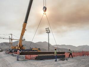 Workers move iron girders from a crane at the GERD on 26 December (AFP)