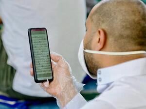 Jordanian man wearing gloves uses cell phone to read Koran inside Mohammad al-Tilawy Mosque in capital Amman recently (AFP)