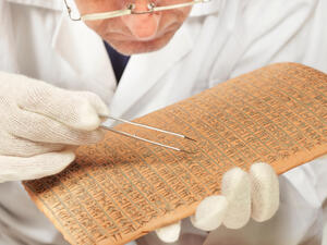 Scientist exploring ancient type of Akkad empire style cuneiform with tweezers. (Shutterstock/ File Photo)