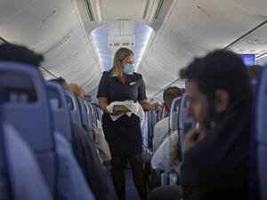 A flight attendant hands out chocolates with a greeting card to passengers on an El Al plane from Israel en route to Abu Dhabi, on August 31, 2020. (AFP)
