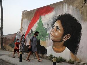 Mask-clad pedestrians walk past a mural painting on September 4, 2020, depicting a young Lebanese girl who suffered a face injury in the August 4 massive blast at the nearby seaport, one month after the disaster that left scores of people dead or injured and ravaged swaths of the capital Beirut. JOSEPH EID / AFP