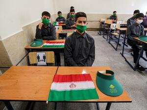 School children sit together in a classroom while mask-clad and distanced apart from each other, new COVID-19 coronavirus pandemic school precautions, with Iranian national flags on the desk of each, on the first day of schools re-opening, at Nojavanan school in the capital Tehran on September 5, 2020. ATTA KENARE / AFP