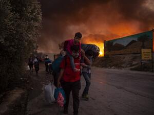 People with children flee flames after a major fire broke out in the Moria migrants camp on the Greek Aegean island of Lesbos, on September 9, 2020. ANGELOS TZORTZINIS / AFP