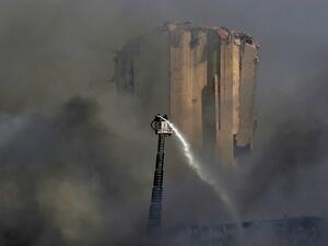 Lebanese firefighters stand on a ladder amid billowing smoke as they extinguish the remaining flames at the seaport of Beirut, on September 11, 2020, a day after a huge fire erupted in harbour warehouses. ANWAR AMRO / AFP