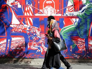 A couple, wearing protective masks amid the COVID-19 pandemic, walks past a mural painted on the outer walls of the former US embassy in the Iranian capital Tehran on September 20, 2020. Iran called on the rest of the world to unite against the United States, after Washington unilaterally declared UN sanctions against the Islamic republic were back in force. Washington has said it will "impose consequences" on any country not complying with the sanctions, although the US is one of the only nations that beli