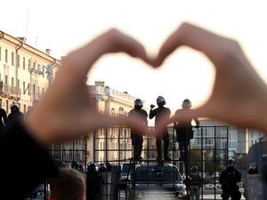 A woman gestures making a heart shape as she stands in front of law enforcement officers blocking the road during a demonstration called by opposition movement for an end to the regime of authoritarian leader in Minsk on September 20, 2020. Belarus President Alexander Lukashenko, who has ruled the ex-Soviet state for 26 years, claimed to have defeated opposition leader Svetlana Tikhanovskaya with 80 percent of the vote in the August 9, elections. STRINGER / AFP