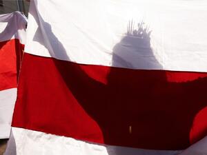 A woman carries a former white-red-white flag of Belarus as she parades through the streets during an opposition rally to protest against the presidential inauguration in Minsk on September 26, 2020. Belarus leader Alexander Lukashenko held his presidential inauguration in secret on September 23, 2020, after claiming victory in disputed polls that his opposition rivals have described as massively rigged. STRINGER / AFP