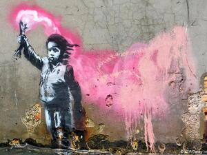 An alleged Banksy work depicts a migrant child wearing a lifejacket holding a pink flare. It is painted on the wall of a house overlooking the Rio de Ca Foscari canal in Venice (AFP/Getty)