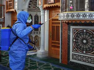 A worker dressed in personal protective equipment sterilizes the mihrab of a mosque in Jordan's capital Amman on June 3, 2020, ahead of its reopening. Photo by KHALIL MAZRAAWI/AFP via Getty Images.