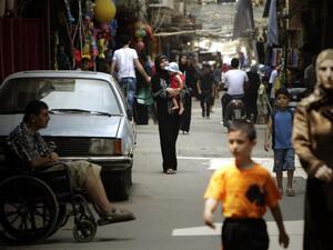 Palestinians walk along a shopping street in the Beddawi refugee camp in Tripoli in August 2010 (AFP)