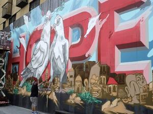 Now the dark surface is decorated by a bright mural centering on the word “hope” in large red letters, with a pair of doves sitting in front. (AFP)