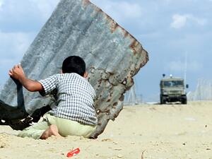 In this file photo taken on October 24, 2000, a Palestinian child takes cover behind a sheet of corrugated iron during clashes in Khan Yunes in the Gaza Strip. THOMAS COEX / AFP
