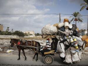 A Palestinian man collects plastic containers on his horse cart while wearing a protective mask due to the COVID-19 coronavirus in Deir al-Balah in the central of Gaza Strip on October 1, 2020. MOHAMMED ABED / AFP