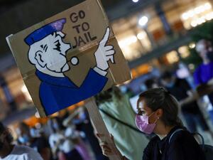 An Israeli anti-government protester carries a placard during a demonstration against Prime Minister Benjamin Netanyahu and against the second nationwide lockdown imposed by the government in a bid to stem the increase of COVID-19 infection cases, in the coastal city of Tel Aviv, on October 3, 2020. JACK GUEZ / AFP