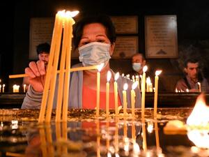 A woman lights a candle during a Sunday service in Yerevan's Saint Sarkis church on October 4, 2020. AFP