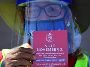 A Democratic Party canvasser holds up campaign material while knocking on doors in the suburbs of Phoenix, Arizona, October 15, 2020 to encourage people to vote in the November 3 presidential and congressional elections. The canvassers, many of whom lost their jobs in LA because of the pandemic, earn up to 20 dollars an hour and keep their health insurance. Their main focus has been to zoom in on working-class neighborhoods where voter turnout is usually low, but the Biden activists also venture into more w