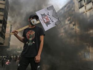 An Iraqi protester carries a placard reading in Arabic "Revolt" during a demonstration on the Sinak bridge in the capital Baghdad on October 25, 2020, marking the first anniversary of a mass anti-government movement. AHMAD AL-RUBAYE / AFP