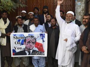 Demonstrators shout slogans and hold a poster with a picture of French President Emmanuel Macron with a footprint over his face during a protest following Macron's comments of Macron over Prophet Mohammed caricatures, in Quetta on October 26, 2020. (AFP)