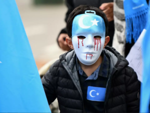 A boy wearing a blue mask with tears of blood takes part in a protest march of ethnic Uighurs, in Brussels on April 27, 2018, asking for the European Union to call upon China to respect human rights. (Emmanuel Dunand, AFP)