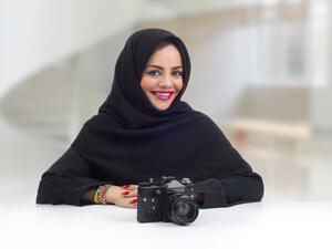 Ambitious Arabian photographer posing with her professional camera (Shutterstock)