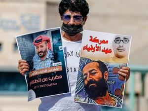 An Israeli left-wing activist lifts posters during a demonstration calling for the release of Palestinian administrative detainees, including Maher al-Akhras, (image L) who's health has deteriorated while on hunger strike, during a protest outside the Israeli run Ayalon prison in Ramle near the coastal city of Tel Aviv, on October 24, 2020. AHMAD GHARABLI / AFP