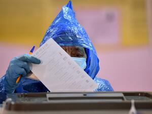 A woman wearing a face mask and gloves casts her ballot at a polling station during Moldova's presidential election in Chisinau on November 1, 2020, amid the ongoing coronavirus disease pandemic. Sergei GAPON / AFP