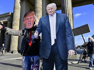 A supporter of US President Donald Trump poses with a cardboard cutout likeness of Trump in front of the Brandenburg Gate as a member of the "Democrats Abroad" organisation (R) walks displaying a placard urging that all ballots be counted, in Berlin on November 4, 2020, as counting continues in the current presidential election. The US election was plunged into chaos early Wednesday November 4, 2020, as President Donald Trump prematurely declared victory and sought Supreme Court intervention to stop vote-co