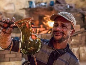 A glassblower sculpts a vessel at a workshop near the 15th century Sultan Qaitbay mosque complex in the "Desert of the Mamluks" (City of the Dead) area of Egypt's capital Cairo on November 1, 2020. In Egypt's "City of the Dead", centuries-old monuments are being restored and artisanal heritage revived, turning a corner of the vast historical cemetery into a vibrant neighbourhood full of life. Since 2014, a series of projects financed by the European Union has changed the face of this small section of the sp
