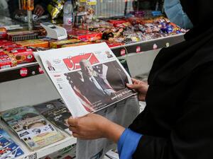 A woman browses the front page of Iranian Farsi newspaper Shargh featuring the 2020 US general election results at a news stand in Iran's capital Tehran on November 8, 2020. ATTA KENARE / AFP