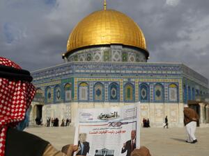 A Palestinian man reads the front page of Al-Quds newspaper, headlined in Arabic "Joe Biden the new US President" in front of the Dome of the Rock in the al-Aqsa mosque compound, Islam's third holiest site, in the old city of Jerusalem on November 8, 2020. AHMAD GHARABLI / AFP
