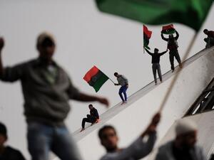 In this file photo taken on March 2, 2011, Libyans wave their old national flag as others celebrate burning copies of the “green book” authored by Libyan ruler Moamer Kadhafi, in the north-central Libyan city of Benghazi. Ten years ago, a wildfire of revolts in the Arab world touched off an unlikely series of events that swelled, then dashed many hopes, and irrevocably changed the region. ROBERTO SCHMIDT / AFP