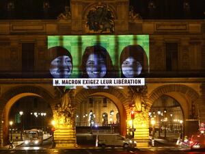 This picture taken early on November 19, 2020, shows a projection on the Louvre Museum in Paris by Amnesty International members depicting jailed Saudi human rights activists including Loujain Al-Athloul (C) and reading "Mr Macron, demand their release", ahead of the upcoming virtual G20 summit. THOMAS COEX / AFP
