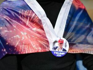 A supporter of President Donald Trump wears a campaign-themed pin to clasp a flag while demonstrating outside of where votes are still being counted, six days after the general election on November 9, 2020 in Philadelphia, Pennsylvania. The state was called for President-elect Joe Biden on Saturday, propelling him past the requisite 270 electoral votes to win the presidency. With 98% of the ballots reported, President-elect Biden leads President Trump by 45,595 votes. Mark Makela/Getty Images/AFP Mark Makel