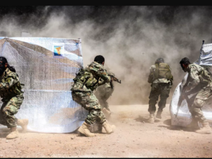 Turkish-backed Syrian fighters perform manoeuvres past tents with posters showing the flags of the Kurdish People's Protection Forces (YPG) during a military exercise on Syria’s northern border with Turkey. (Nazeer al-Khatib, AFP)