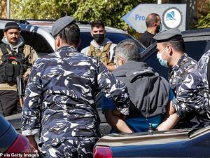 The police in Beirut confirmed 15 inmates has been re-arrested so far and four had handed themselves in. Pictured: Police escort a prisoner who had fled a detention centre. (AFP)