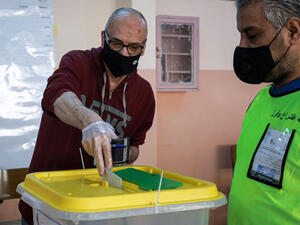 A voter, mask-clad due to the COVID-19 coronavirus pandemic, casts a ballot at a polling station in Jordan's capital Amman on November 10, 2020, KHALIL MAZRAAWI/AFP via Getty Images]