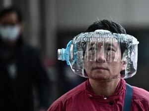 A woman wears a plastic water bottle with a cutout to cover her face, as she walks on a footbridge in Hong Kong on January 31, 2020, as a preventative measure following a virus outbreak which began in the Chinese city of Wuhan. The World Health Organization, which initially downplayed the severity of a disease that has now killed 170 nationwide, warned all governments to be "on alert" as it weighed whether to declare a global health emergency. Anthony WALLACE / AFP