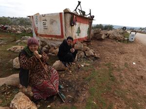 Displaced Syrian who gave his first name as Mahmud sits outside his makeshift tyre repair shop which he covered with a Lebanese flag following Beirut's massive port blast last August, in the village of Kafr Uruq in the north of Syria's rebel-held Idlib province on December 28, 2020. Mahmud kept the flag on his shack despite his disappointment with a dispute that led a group of Lebanese nationals to set fire to an informal Syrian refugee settlement in northern Lebanon on the weekend. Lebanon's army said on D