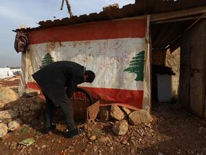 Displaced Syrian who gave his first name as Mahmud works outside his makeshift tyre repair shop which he covered with a Lebanese flag following Beirut's massive port blast last August, in the village of Kafr Uruq in the north of Syria's rebel-held Idlib province on December 28, 2020. Mahmud kept the flag on his shack despite his disappointment with a dispute that led a group of Lebanese nationals to set fire to an informal Syrian refugee settlement in northern Lebanon on the weekend. Lebanon's army said on 