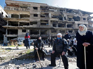 Residents of the Palestinian Yarmuk camp, on the southern outskirts of the Syrian capital Damascus, walk past destroyed buildings on November 25, 2020 as families visit the destroyed residential district.(AFP)