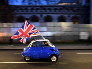 In this file photo taken on January 31, 2020 A man waves Union flags from a BMW Isetta as he drives past Brexit supporters gathering in Parliament Square, in central London on January 31, 2020, the day that the UK formally leaves the European Union. Severing a truculent partnership stretching back five decades, Britain finally went its own way late Thursday four-and-a-half years after its shock referendum verdict in favour of divorcing the EU. Brexit became reality as Big Ben struck 11:00 pm (2300 GMT) in c