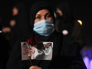 An Iraqi woman carries a portrait of late Iraqi commander Abu Mahdi al-Muhandis and Iranian commander Qasem Soleimani at Baghdad Airport, in Baghdad on January 2, 2021, at the site of their killing. On January 3, 2021, Iraq will mark the first anniversary of the killing of Iran's top military commander Qasem Soleimani in a drone strike at Baghdad International Airport that was authorized by US President Trump. AFP