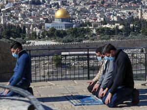 Mask-clad Palestinians, unable to reach the Al-Aqsa mosque compound amidst strengthened restriction due to the coronavirus, perform Friday prayers at the Mount of Olives overlooking the compound in the Old City of Jerusalem, on January 22, 2021. AHMAD GHARABLI / AFP