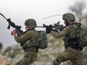 Israeli soldiers hold up their rifles towards Palestinian protesters in the village of Kfar Qaddum, near Nablus in the occupied West Bank (AFP File Photo)
