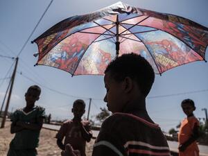 An Eritrean refugee child stands under an umbrella at Mai Aini Refugee camp, in Ethiopia, on January 30, 2021. Eritrean refugees in Ethiopia fear their suffering may not be over, as Prime Minister Abiy Ahmed strains to end a brutal conflict in the northern region of Tigray that has rendered them uniquely vulnerable. Nearly 100,000 refugees from Eritrea, an oppressive, authoritarian nation bordering Ethiopia to the north, were registered in four camps in Tigray when fighting erupted in November between Abiy'