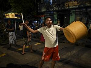 A man hits a plastic container to make noise after calls for protest went out on social media in Yangon on February 3, 2021, as Myanmar's ousted leader Aung San Suu Kyi was formally charged on Wednesday two days after she was detained in a military coup. STR / AFP
