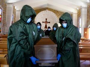 Members of Lebanon's Shiite Hezbollah movement's Islamic health unit, transport the coffin of a Lebanese Christian woman who died of the COVID-19 disease, out of a church to be inhumated in a nearby cemetary, near the southern Lebanese town of Bint Jbeil, on February 5, 2021.  Mahmoud ZAYYAT / AFP